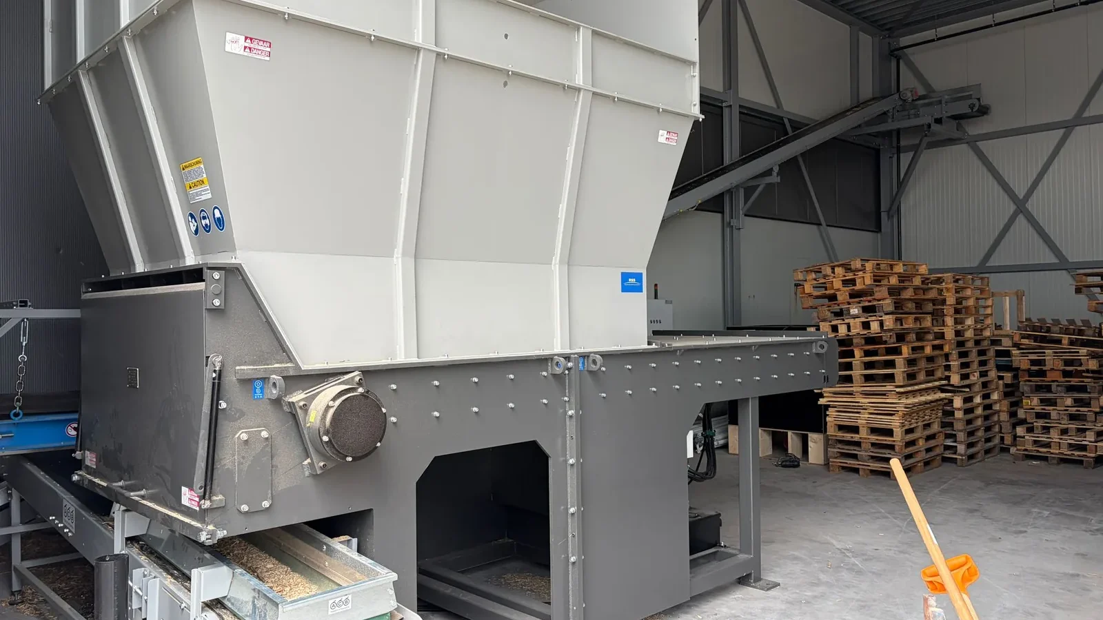 Single shaft shredder van RSS met grote invoertrechter en afvoerband in een loods